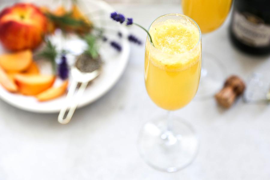 Bellini in a champagne flute next to a plate of peaches.