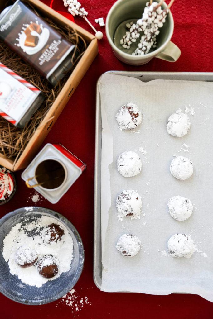 A photo of crinkle cookies on a cookie sheet before they are baked surrounded by ingredients